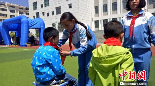 图为西宁市南川西路小学的少先队员向儿童福利院的小朋友佩戴红领巾。　张海雯 摄