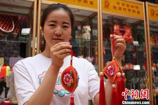 图为在甘肃省妇联陇原巧手体验馆内，工作人员展示新制作的香包。　徐雪 摄