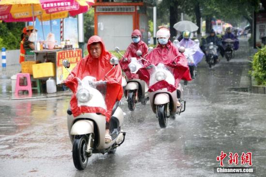 6月16日，广西柳州市遭暴雨侵袭，民众穿着雨衣骑电动车出行。 记者 朱柳融 摄