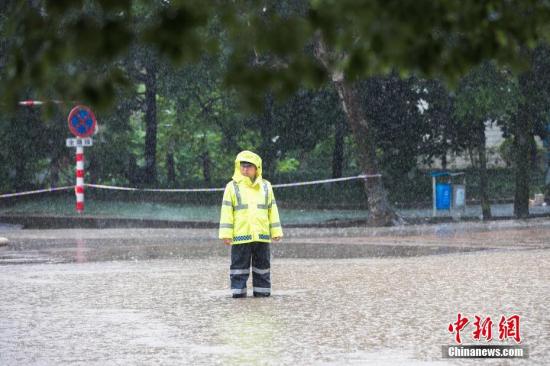 资料图：6月13日，浙江省金华市浦江县大雨倾盆，交警冒雨执勤，阻拦车辆进入漫水路段。 发 张浩钺 摄